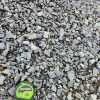 An overhead shot of a pile of gray crushed stone. The rocks are a mix of light and dark gray, with some brown and tan pieces mixed in. A green and black "CRAFTSMAN 25'" tape measure is in the bottom left corner, providing a sense of scale for the size of the rocks.