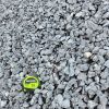 An overhead photo of a pile of gray crushed stone. A green and black "CRAFTSMAN 25'" tape measure is in the bottom center, providing a sense of scale. The rocks are irregular and angular, and they appear to be a mix of light and dark gray tones.