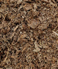 A close-up overhead shot of a pile of rich, dark brown soil or compost. The mix is composed of various textured materials, including wood chips, leaves, and other organic matter.